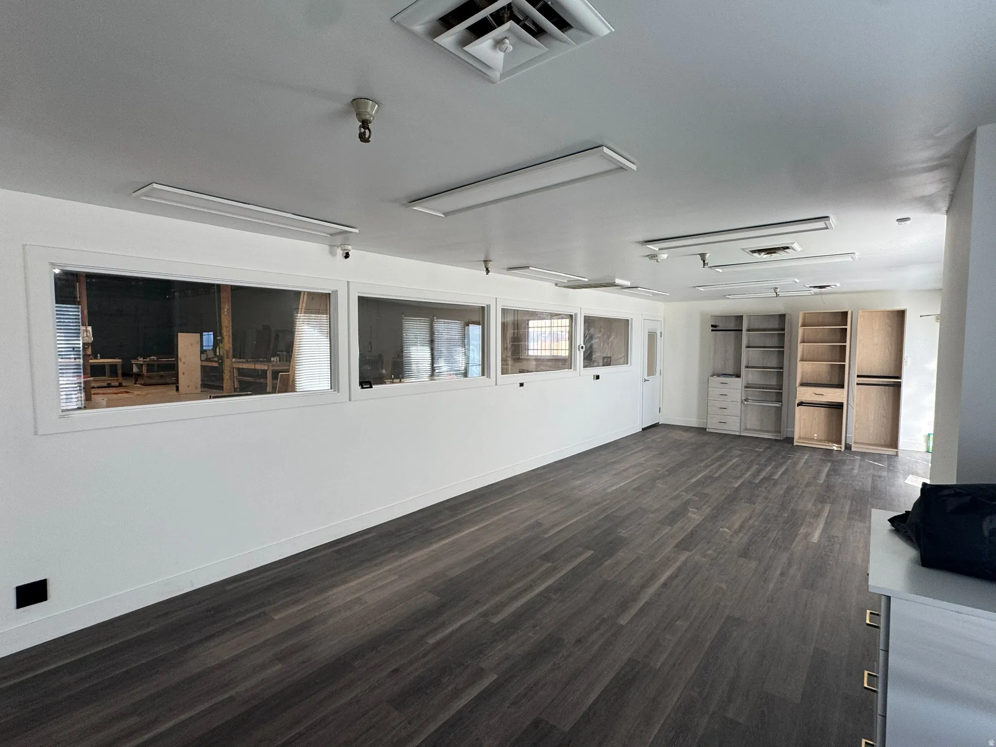 Unfurnished living room with dark wood-style flooring and baseboards