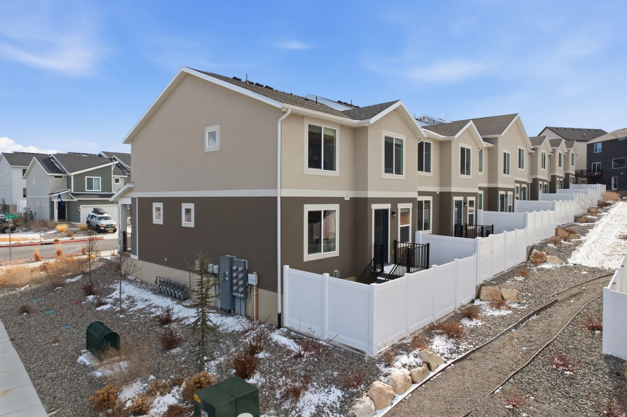 View of walking path and open grassy area between townhome and single-family homes