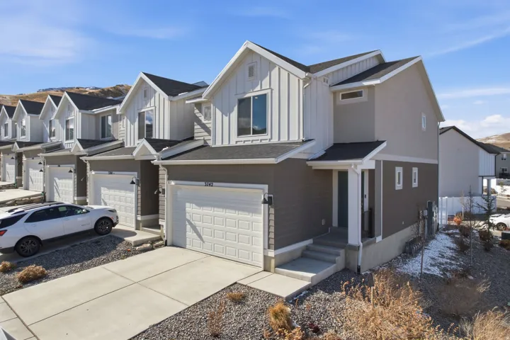 View of front of property with an attached garage, a residential view, board and batten siding, and driveway