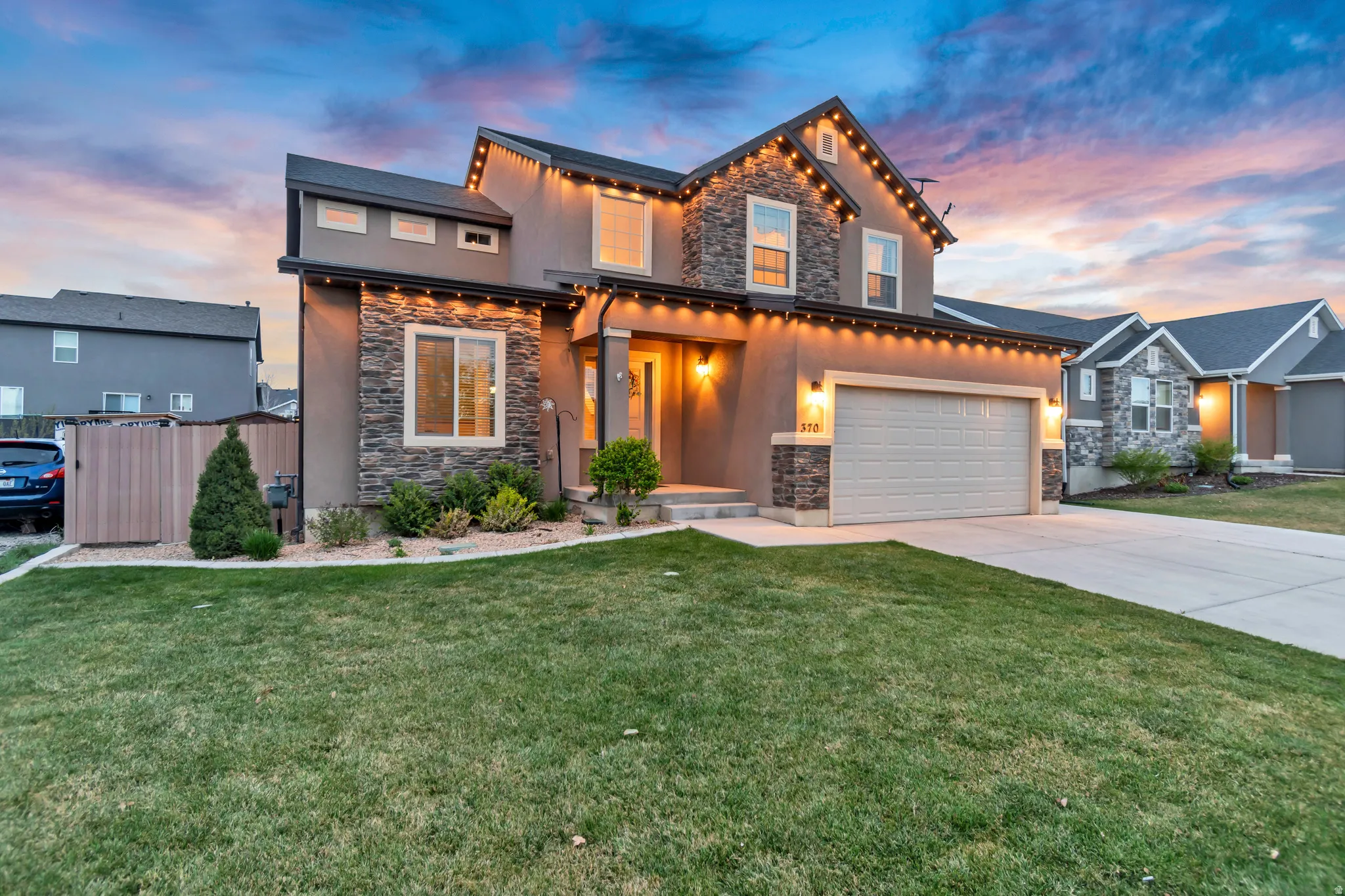 View of front of property with stone siding, driveway, a yard, and a garage