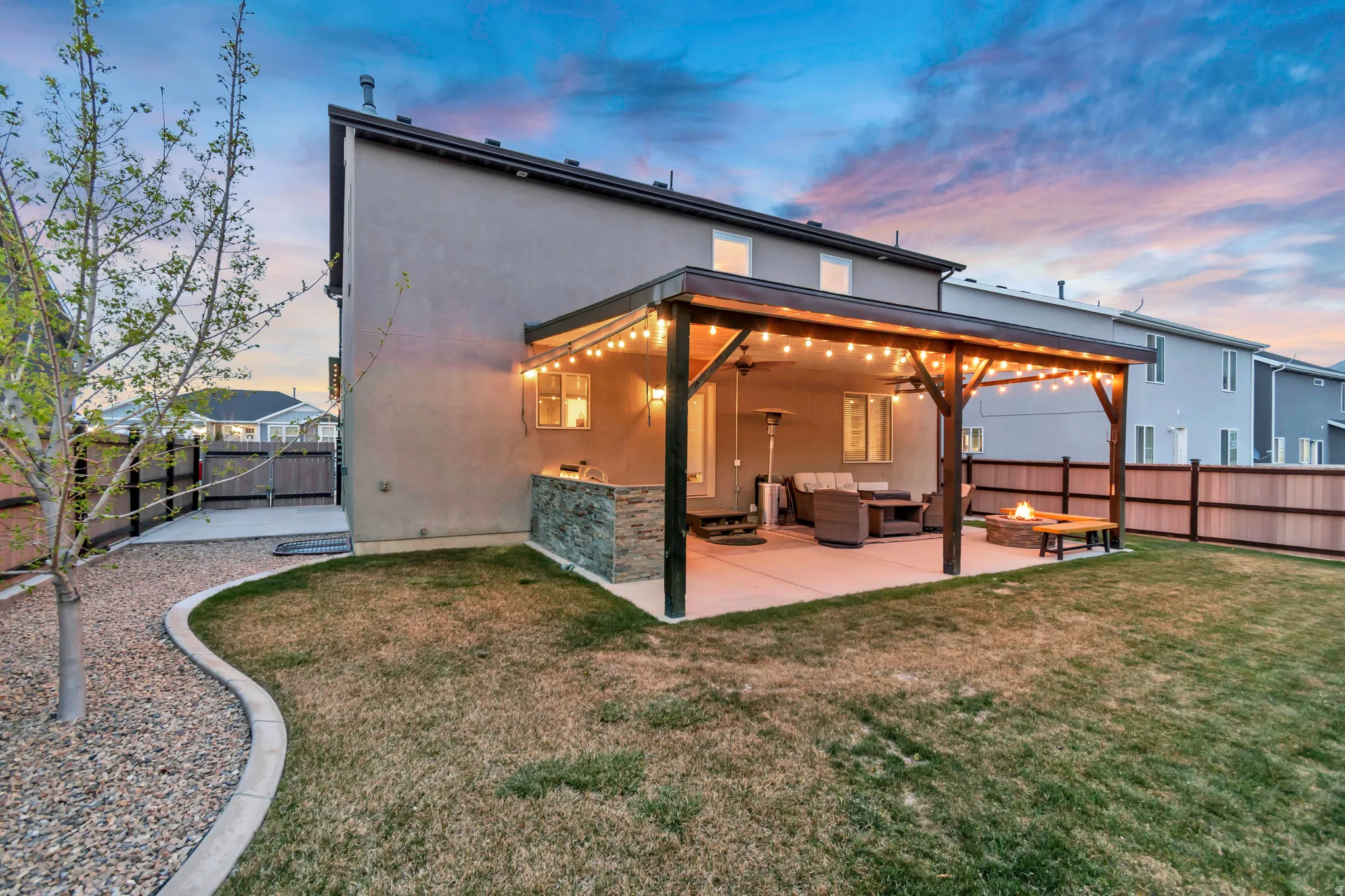 Rear view of property with stucco siding, an outdoor living space with a fire pit, a patio, a fenced backyard, and ceiling fan