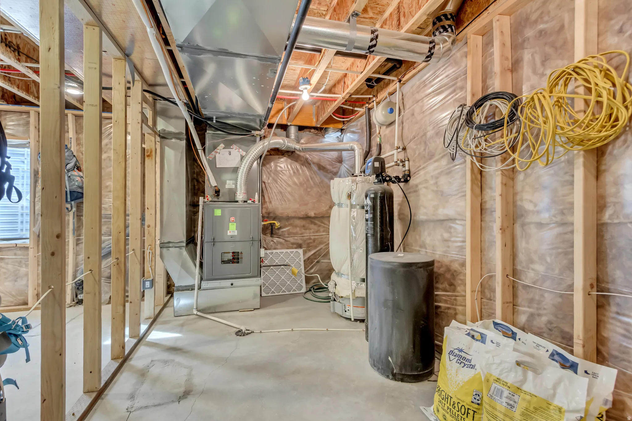 Unfinished below grade area with a water softener and water heater