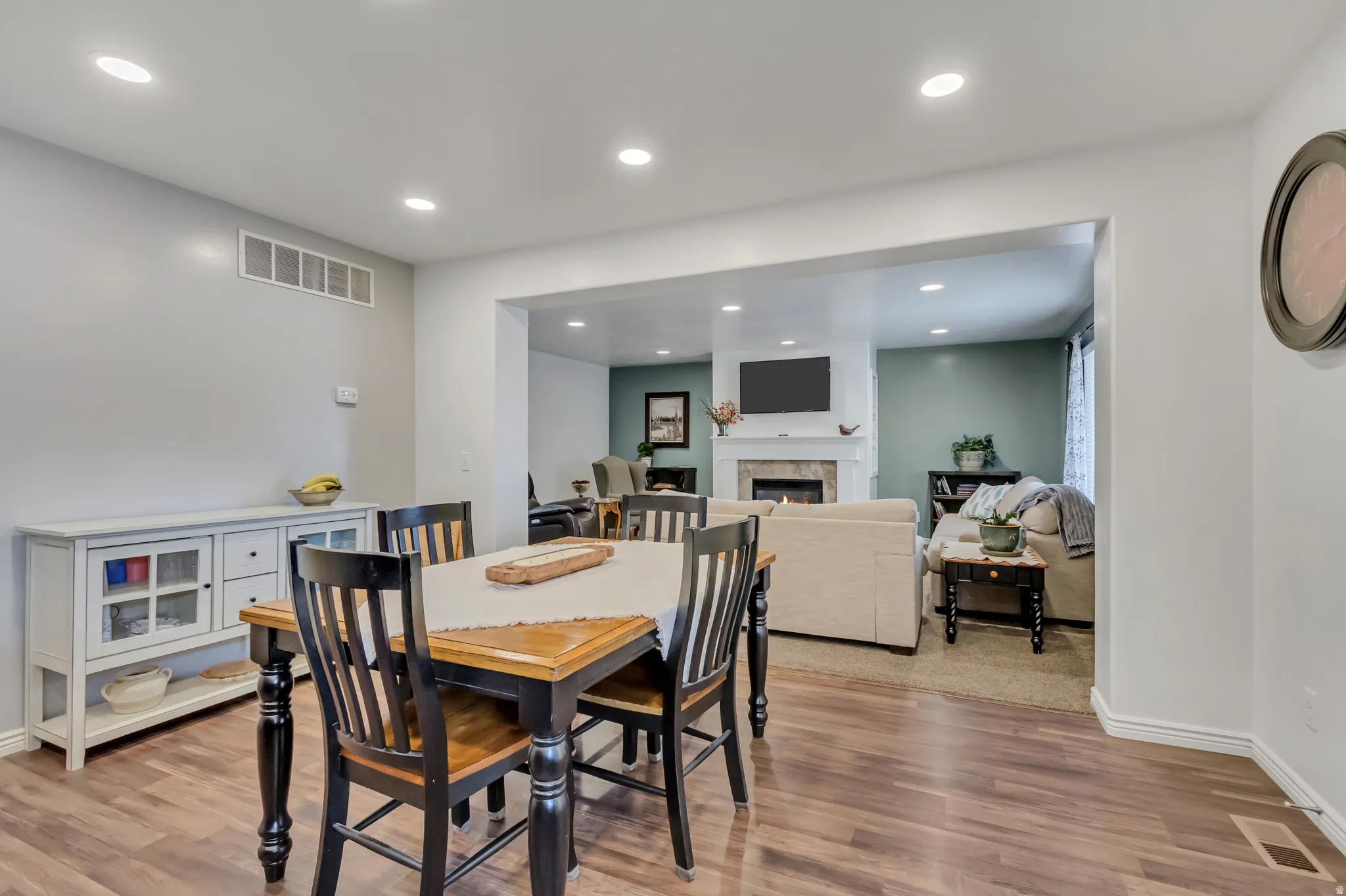 Dining space featuring a warm lit fireplace, light wood-type flooring, and recessed lighting