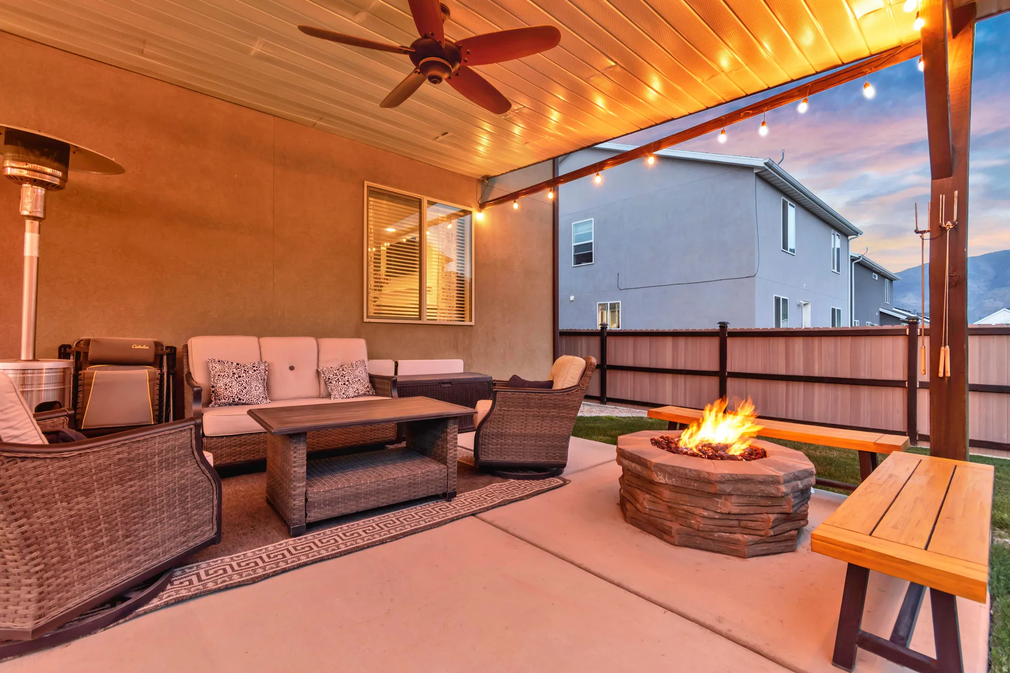 Patio terrace at dusk with ceiling fan, a patio area, and an outdoor living space with a fire pit