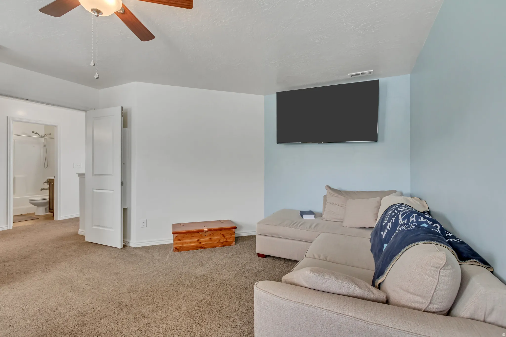 Carpeted living room with a ceiling fan and a textured ceiling