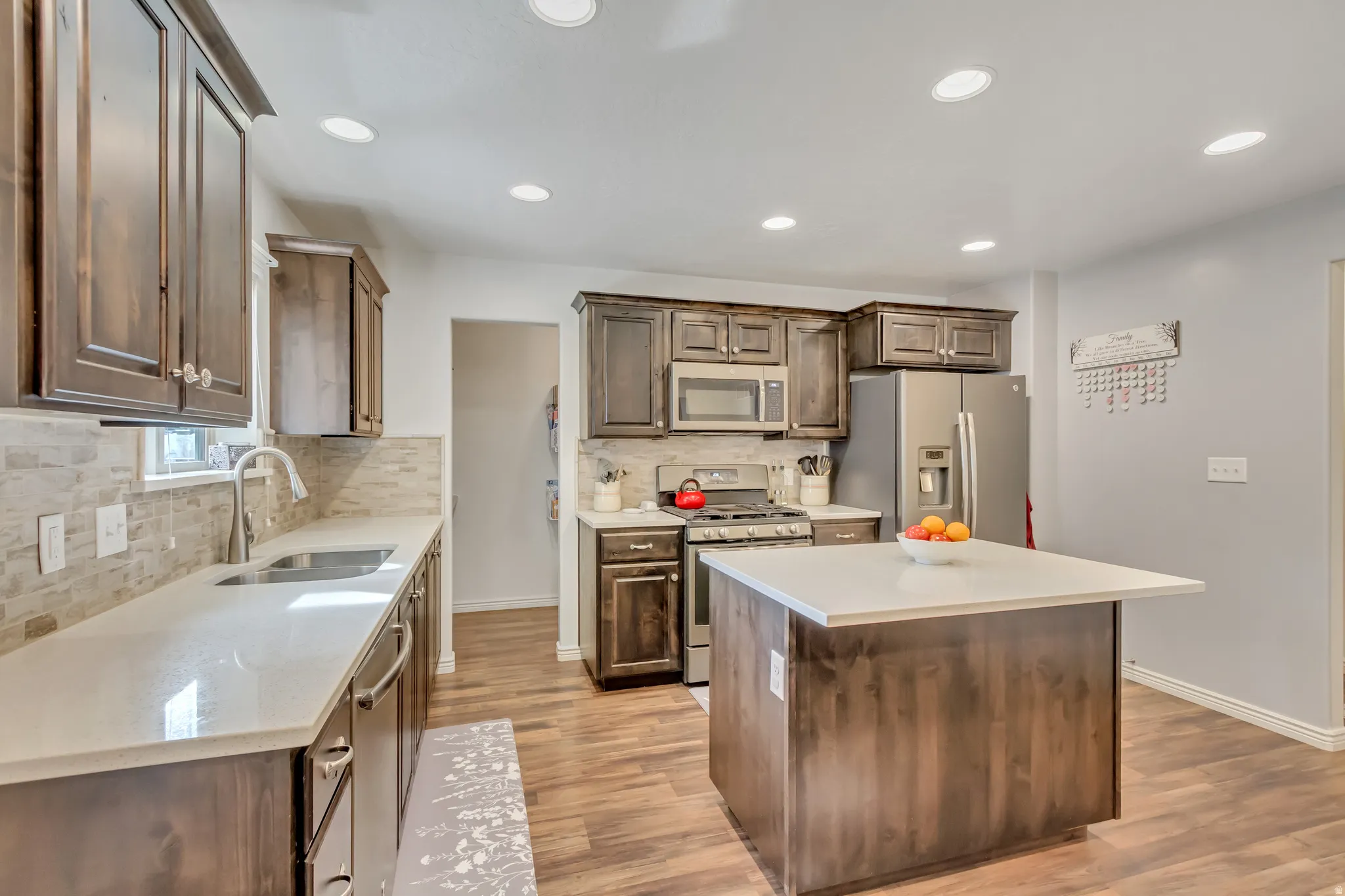 Kitchen featuring stainless steel appliances, tasteful backsplash, a center island, light wood-style floors, and recessed lighting