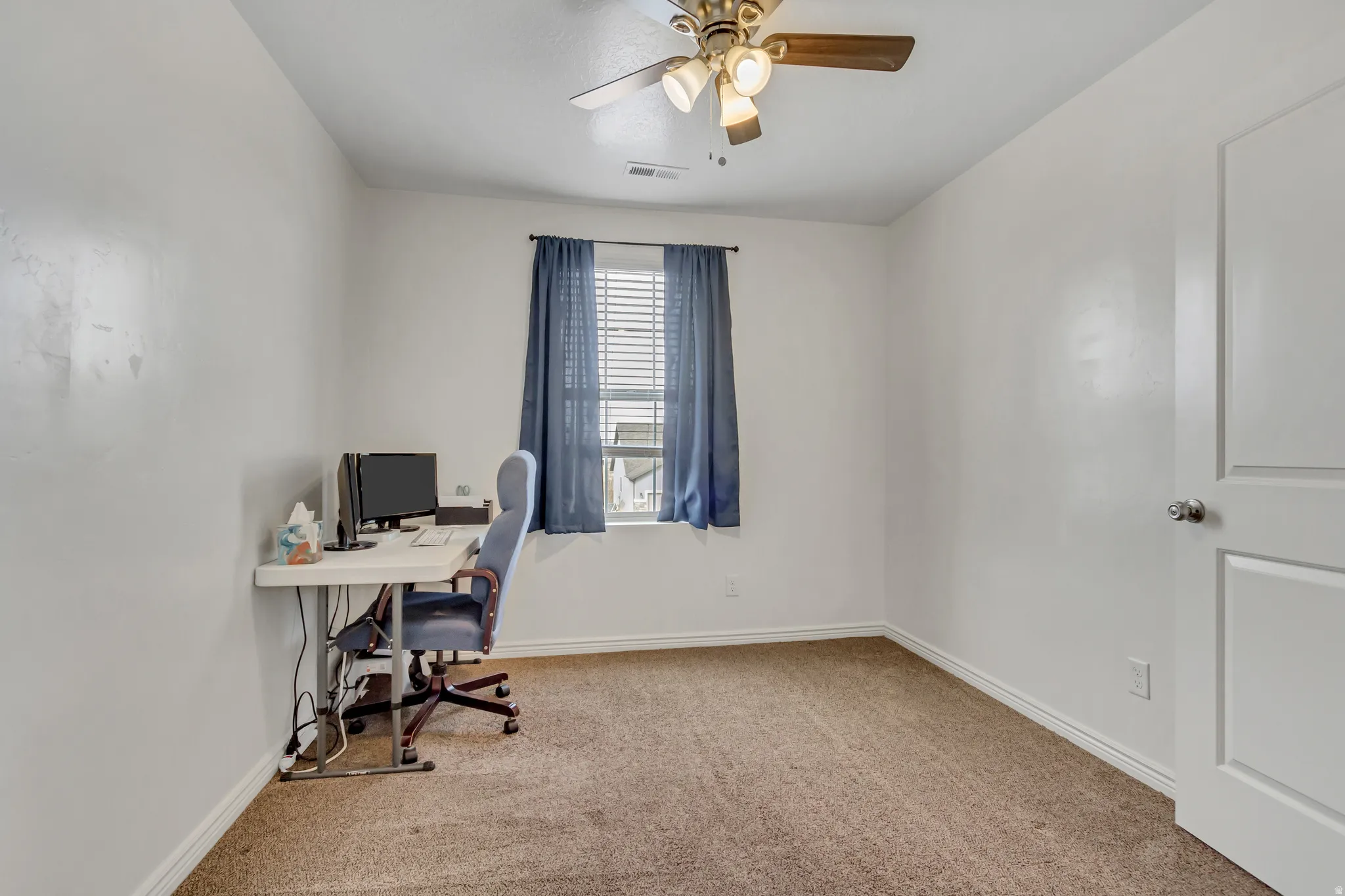 Office area featuring light colored carpet and ceiling fan