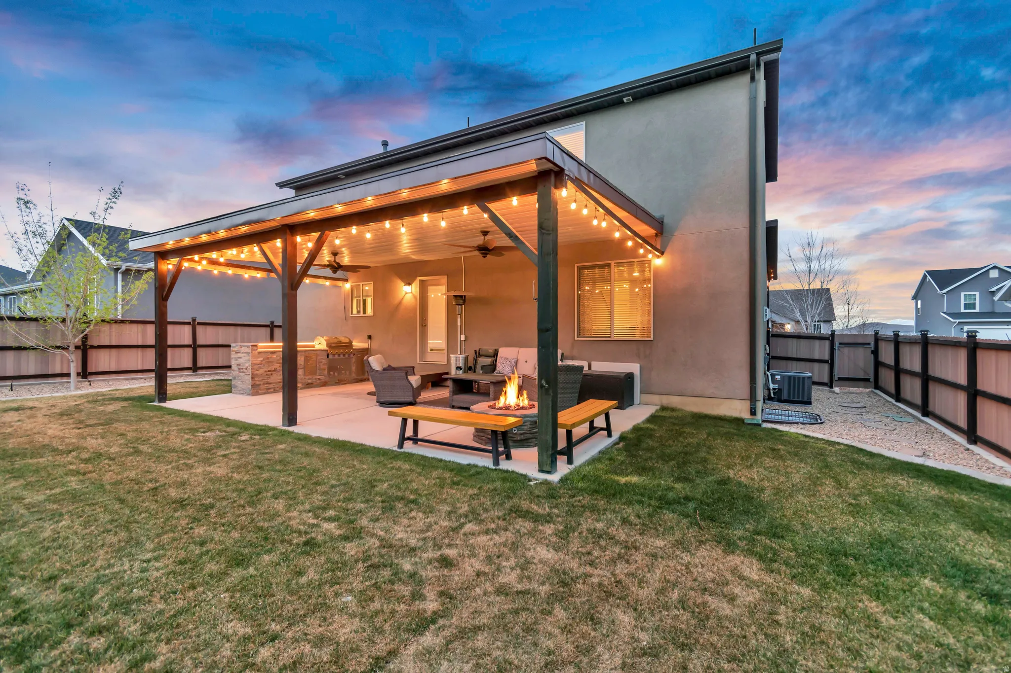Back of house at dusk with a patio area, a ceiling fan, a fenced backyard, and stucco siding