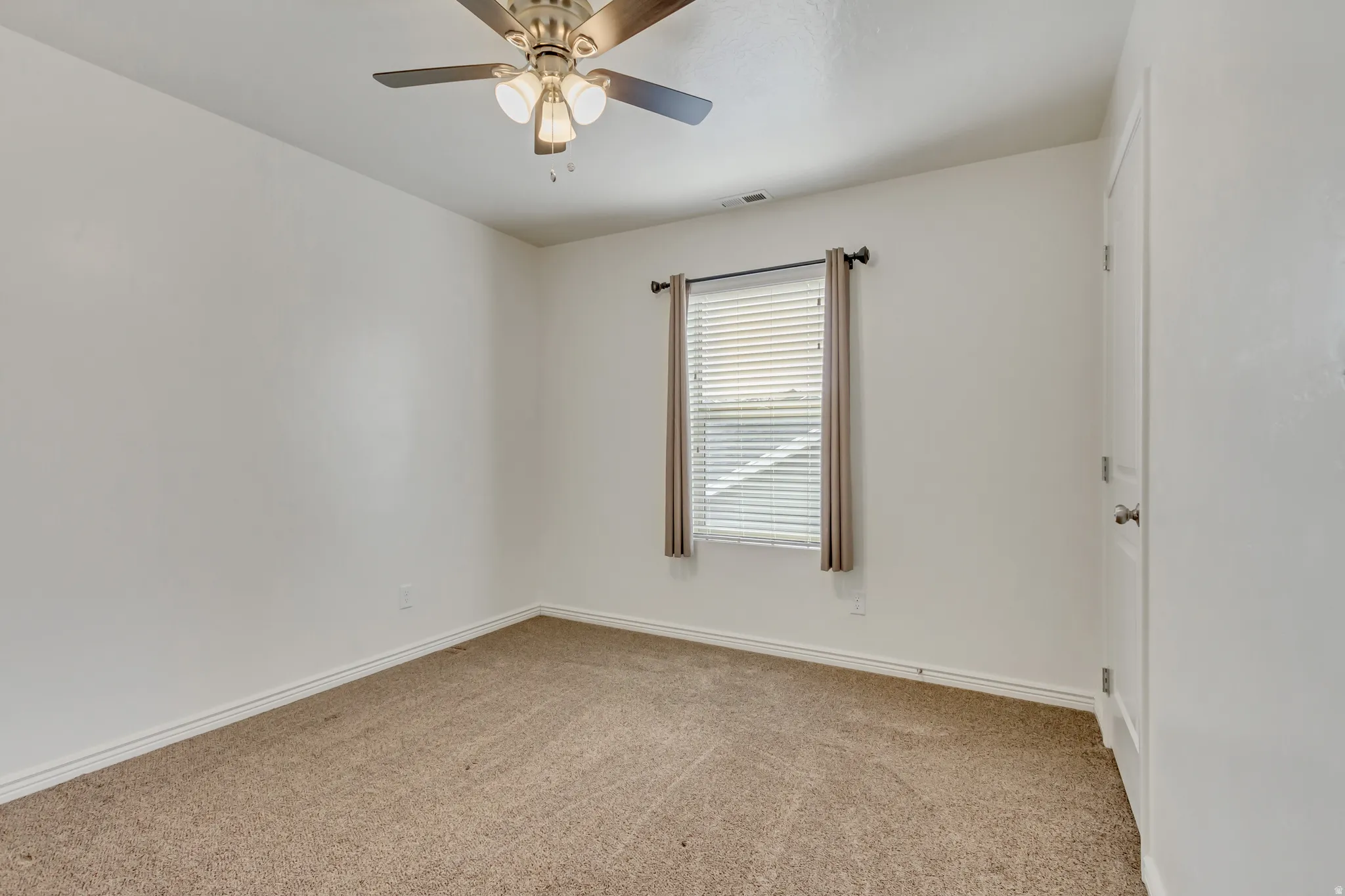 Empty room with light carpet and a ceiling fan