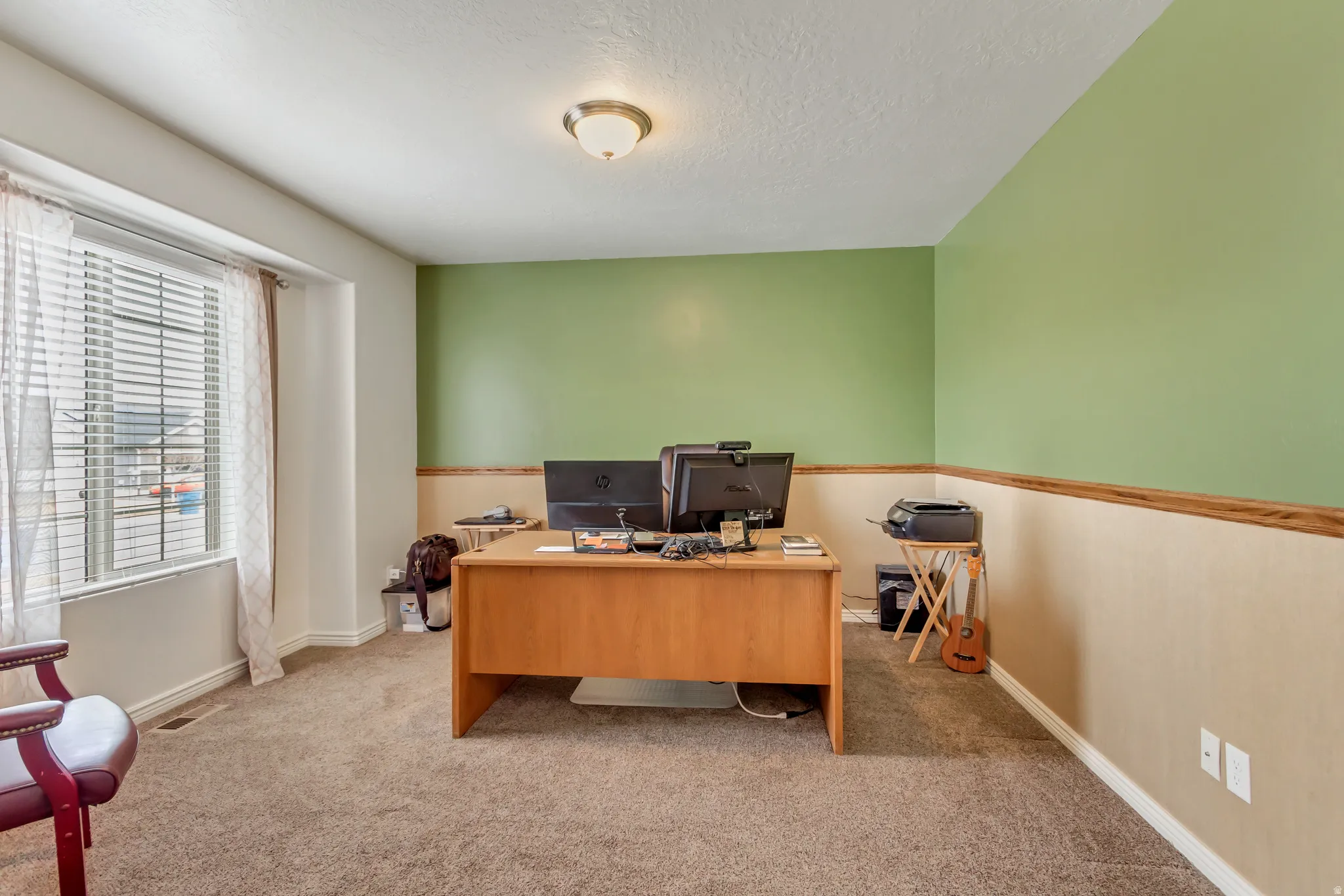 Home office featuring light colored carpet and a textured ceiling