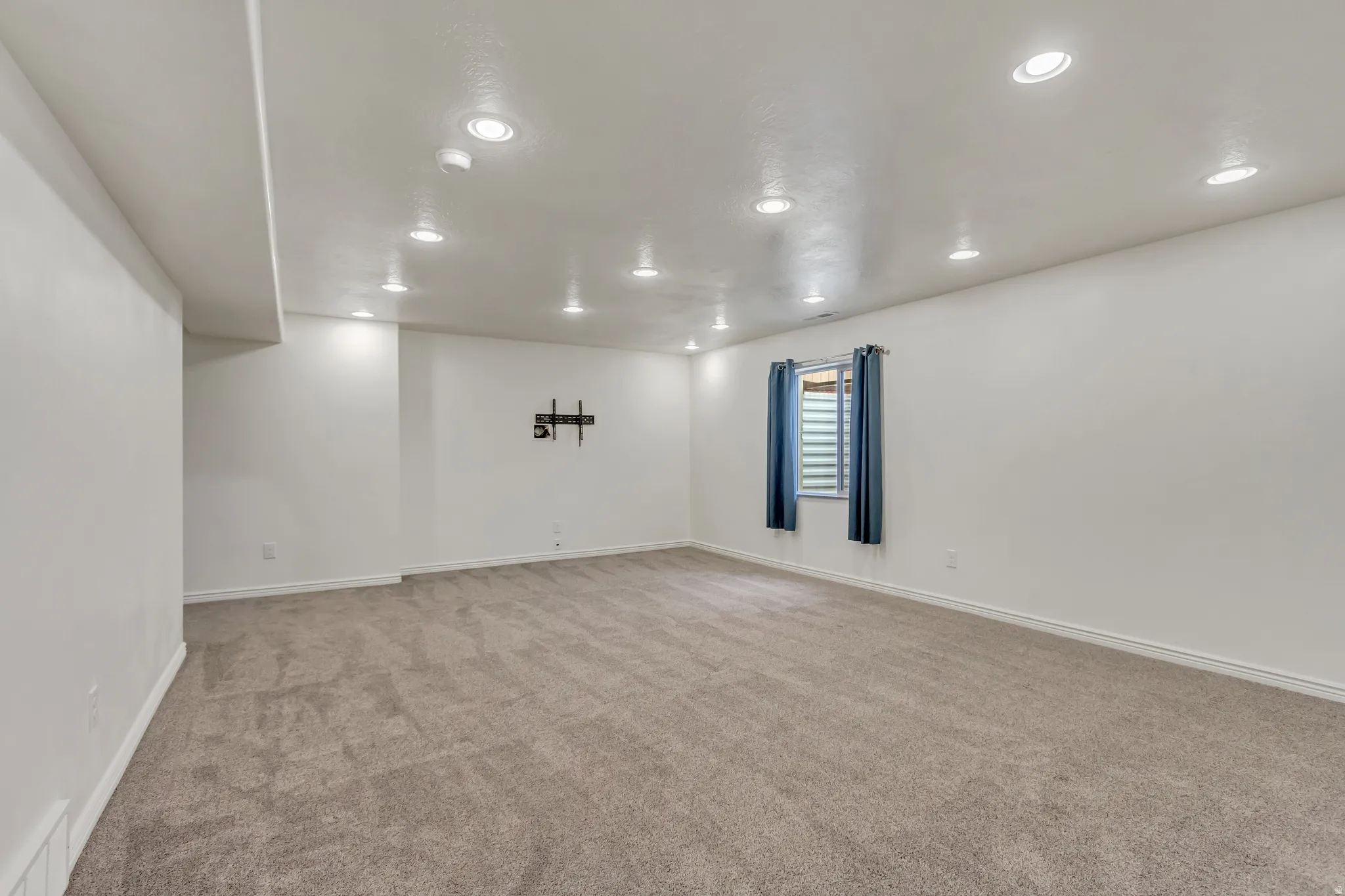 Empty room with light colored carpet and recessed lighting