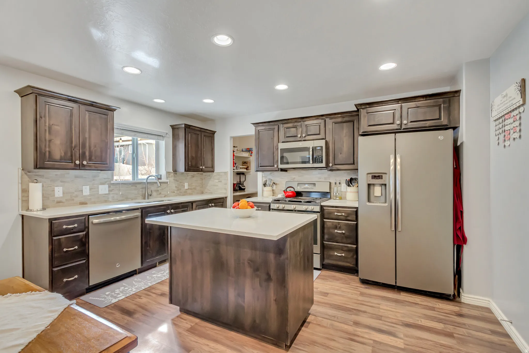 Kitchen featuring stainless steel appliances, dark wood finish cabinets, a kitchen island, tasteful backsplash, and recessed lighting