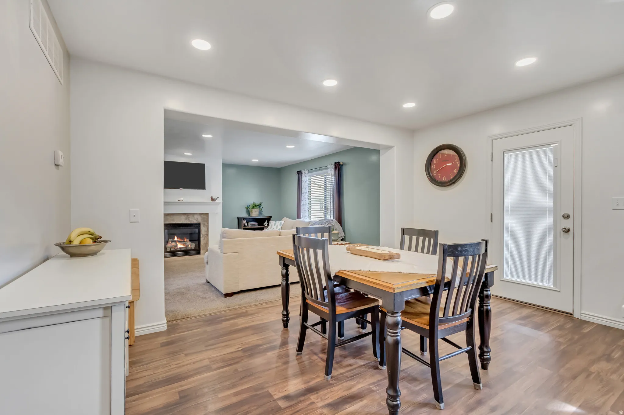 Dining space featuring wood finished floors, a tiled fireplace, and recessed lighting