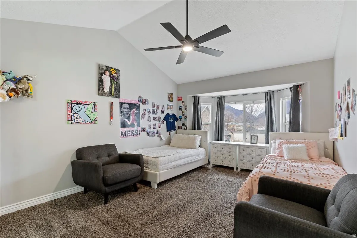 Carpeted bedroom with ceiling fan, a high ceiling, and a mountain view