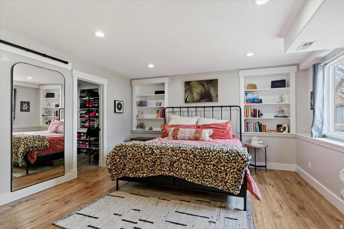 Bedroom featuring a spacious closet, light wood-type flooring, and recessed lighting