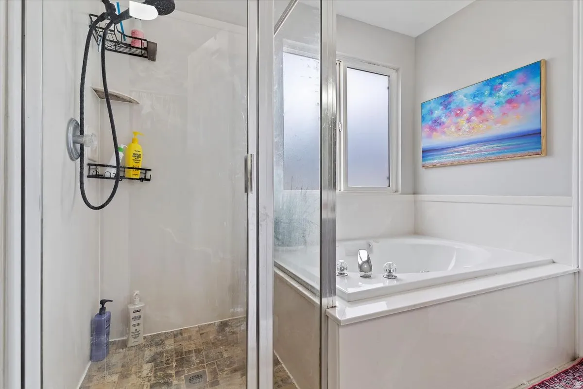 Full bath featuring a shower stall, stone finish flooring, and a garden tub
