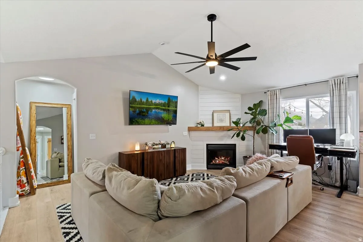 Living room featuring arched walkways, light wood-type flooring, an office area, and a fireplace