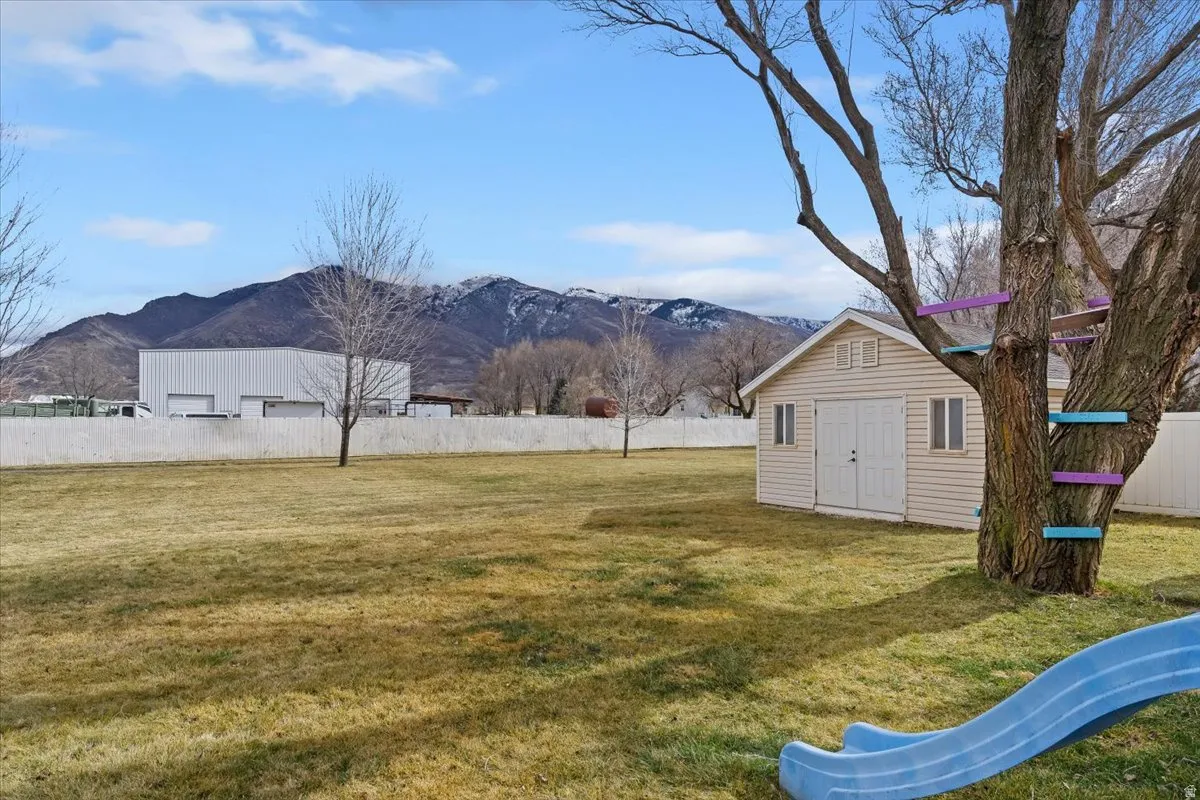 Fenced yard featuring a mountain view and a storage unit