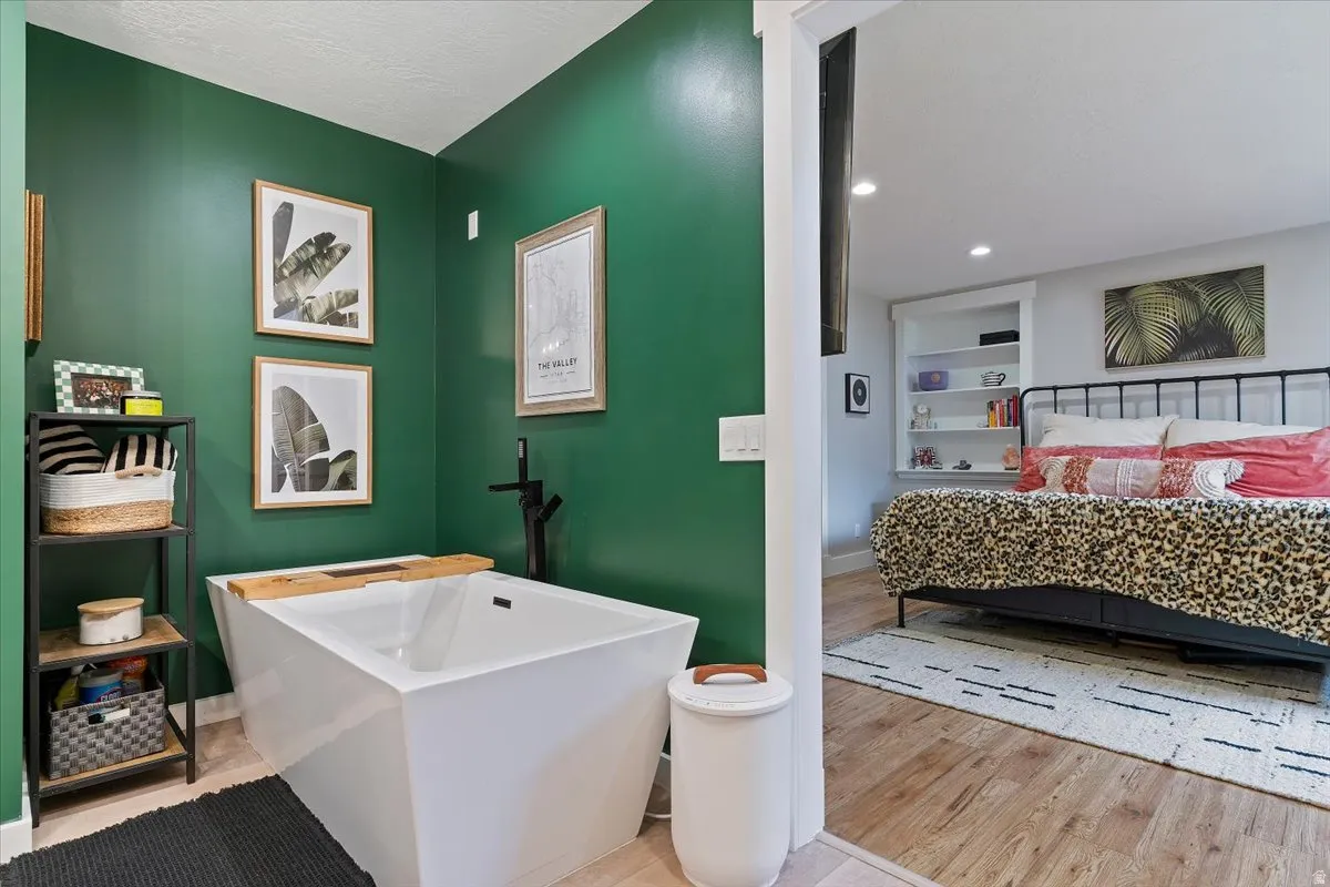 Full bathroom with built in shelves, a soaking tub, and light wood-type flooring