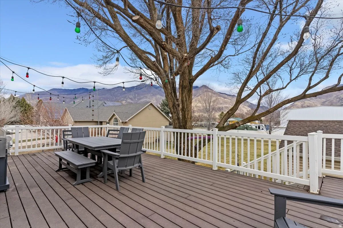 Deck with outdoor dining area, a mountain view, and a grill