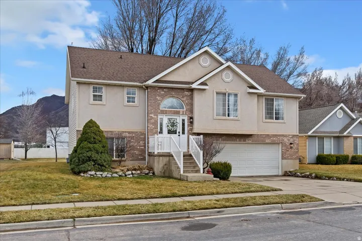 Split foyer home featuring brick siding, stucco siding, and driveway