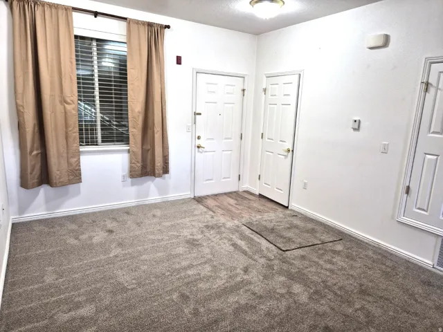 Foyer with dark colored carpet and baseboards