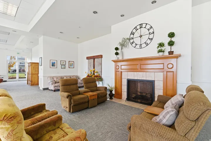 Living room featuring a high ceiling, a fireplace, light carpet, and recessed lighting