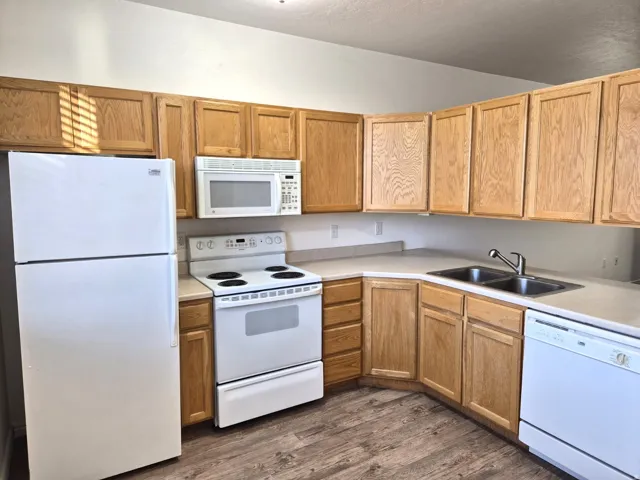 Kitchen featuring white appliances, light countertops, and dark wood-style floors