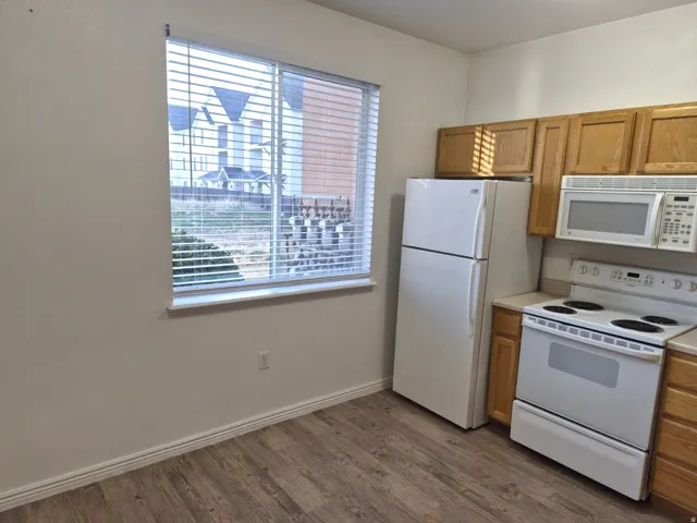 Kitchen with white appliances, light countertops, dark wood-type flooring, and wood finish cabinetry
