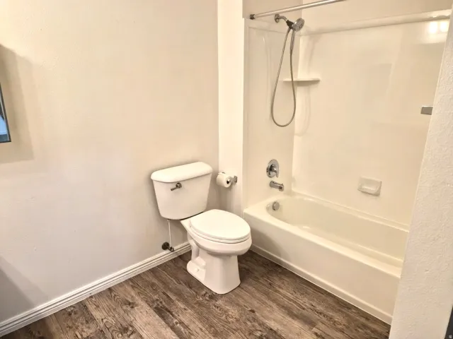 Bathroom with dark wood-type flooring and shower / bathtub combination