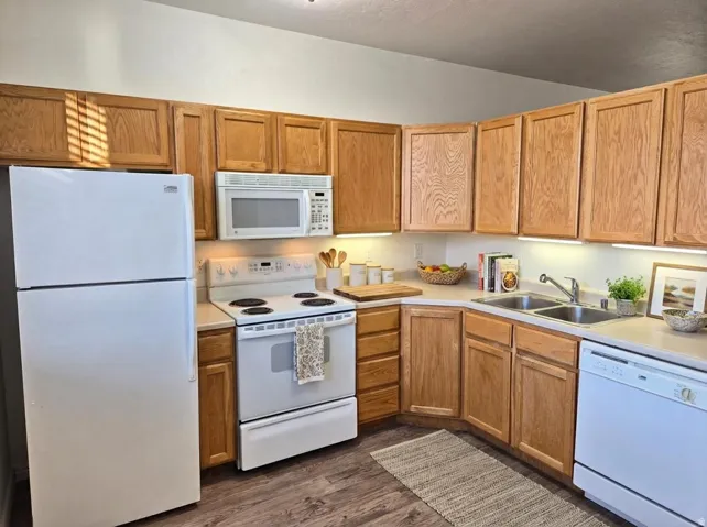 Kitchen with white appliances, light countertops, and dark wood finished floors. Virtual staging