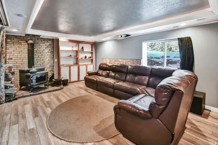 Living area featuring a wood stove, a tray ceiling, recessed lighting, a textured ceiling, and light wood finished floors