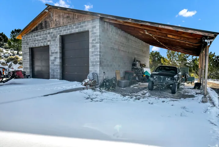 Snow covered garage with a detached garage