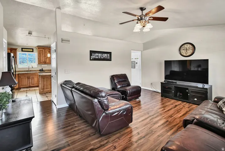 Living area featuring a ceiling fan, dark wood-type flooring, and vaulted ceiling