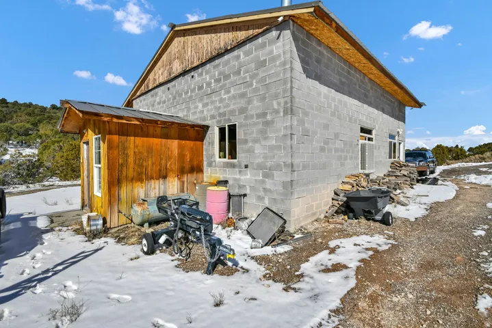 Snow covered property with concrete block siding and an outbuilding
