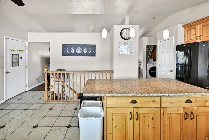 Kitchen with pendant lighting, freestanding refrigerator, washer / dryer, a kitchen island, and a ceiling fan