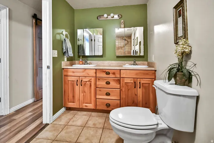 Bathroom featuring double vanity, light tile patterned floors, and a shower