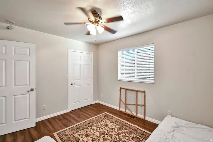 Bedroom with dark wood-type flooring, ceiling fan, and a textured ceiling