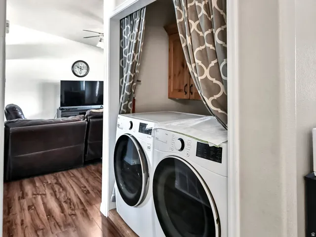 Laundry room with dark wood-style flooring, washing machine and dryer, and cabinet space