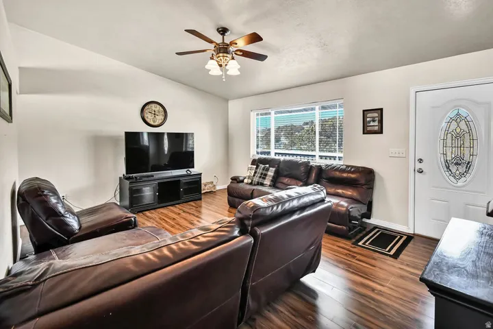 Living room featuring dark wood-style floors, lofted ceiling, and a ceiling fan