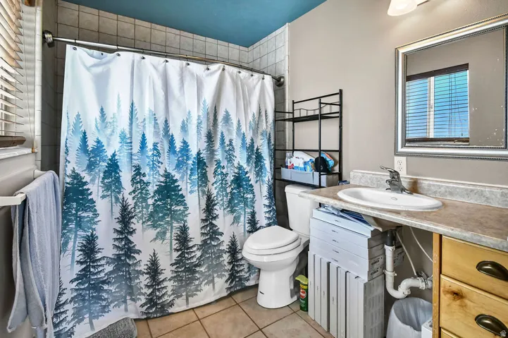 Bathroom with light tile patterned floors, vanity, and a shower with curtain