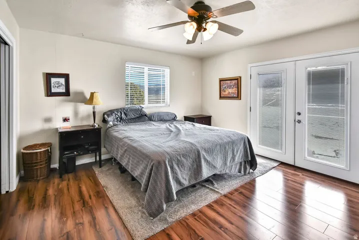 Bedroom featuring french doors, access to exterior, dark wood-style flooring, and ceiling fan