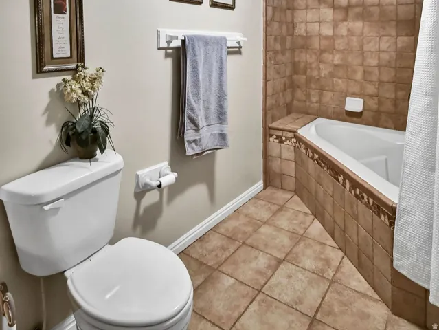 Full bathroom with a textured ceiling, tiled shower / bath, and light tile patterned floors