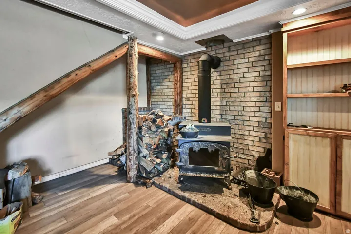 Living room featuring brick wall, light wood-style floors, a wood stove, ornamental molding, and recessed lighting