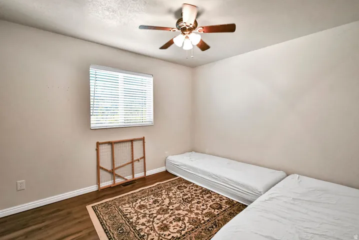 Bedroom with a ceiling fan and dark wood-style floors