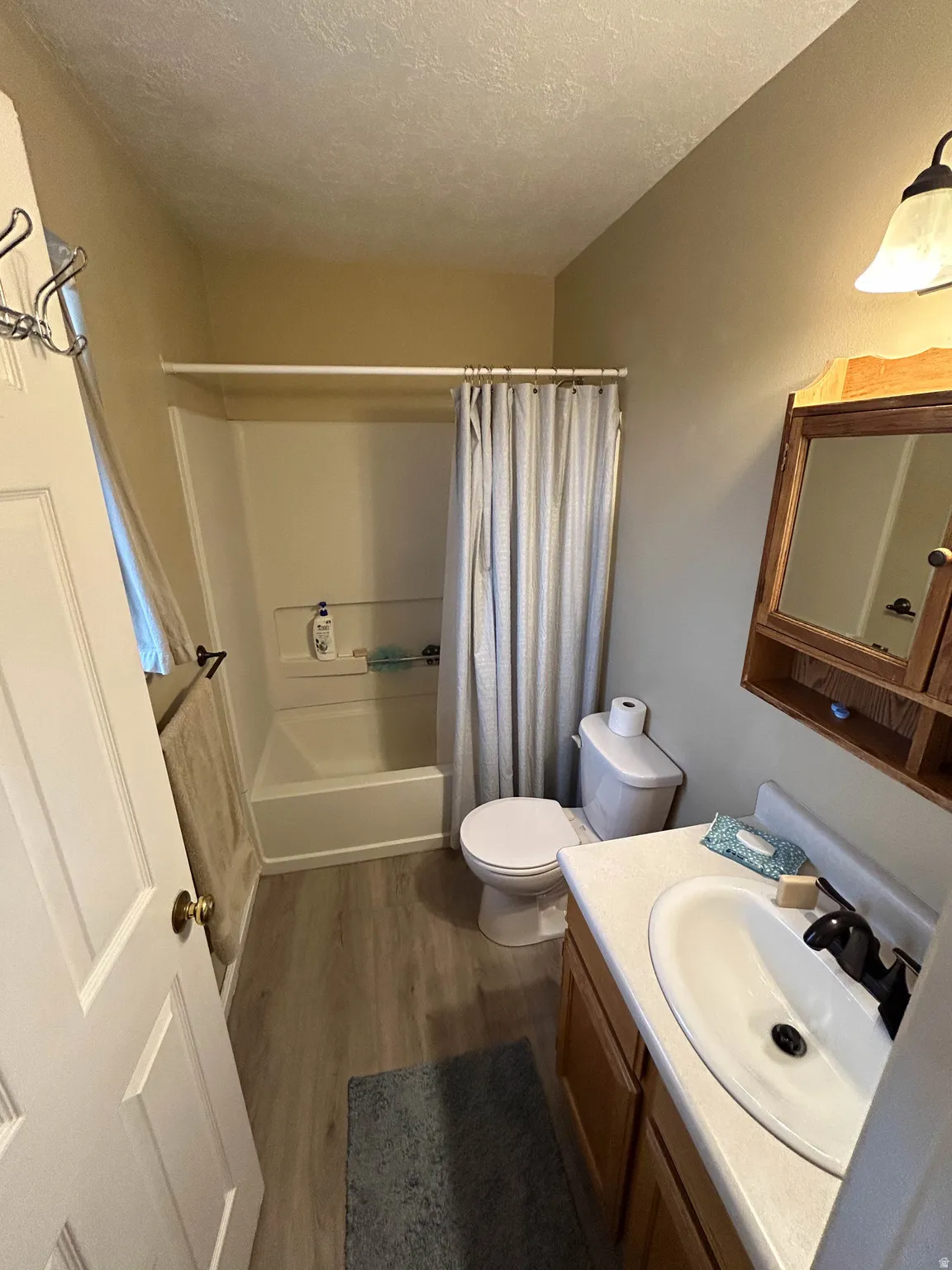 Bathroom featuring vanity, dark wood-style flooring, shower / tub combo, and a textured ceiling