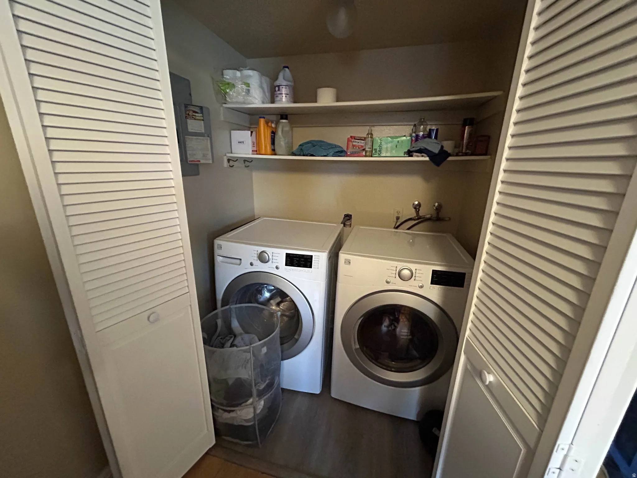 Laundry area with electric panel, washer and dryer, and dark wood-style floors