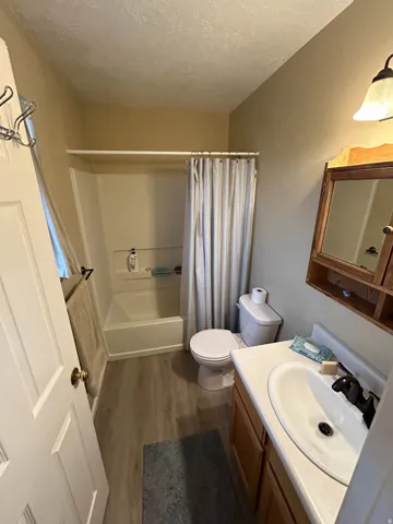 Bathroom featuring vanity, dark wood-style flooring, shower / tub combo, and a textured ceiling