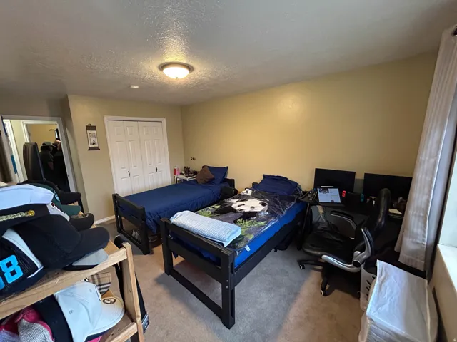 Bedroom with carpet flooring, a closet, a textured ceiling, and an office area