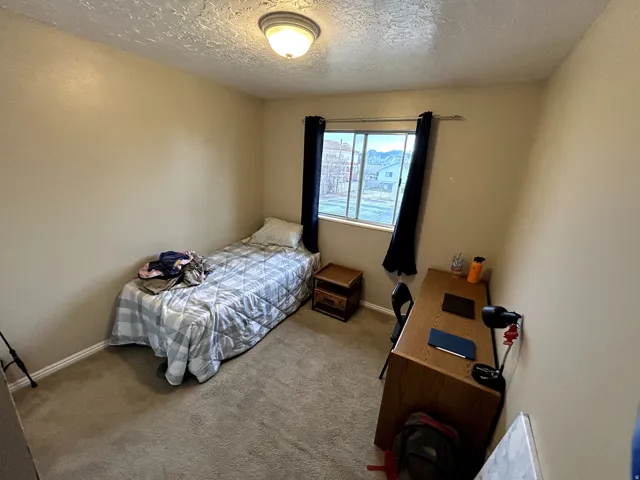 Carpeted bedroom featuring a textured ceiling and baseboards